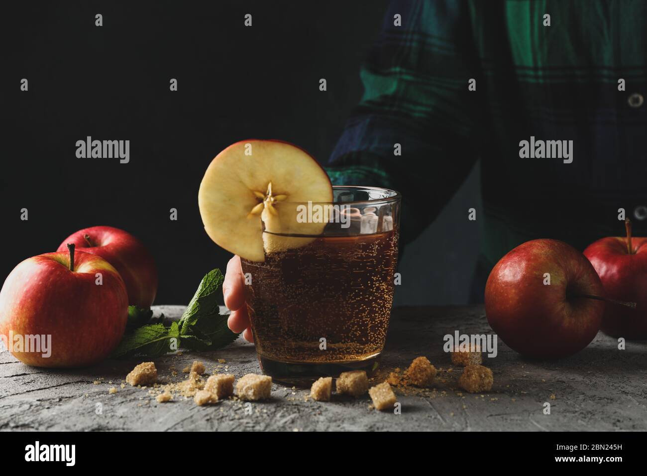 Donna tenere il bicchiere di sidro. Composizione con sidro su tavolo grigio Foto Stock