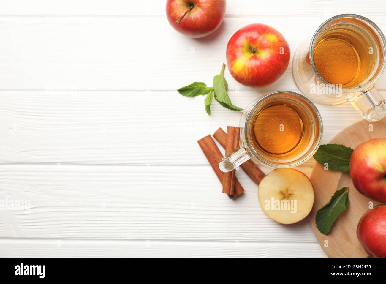 Composizione con sidro, cannella e mele su fondo di legno bianco Foto Stock