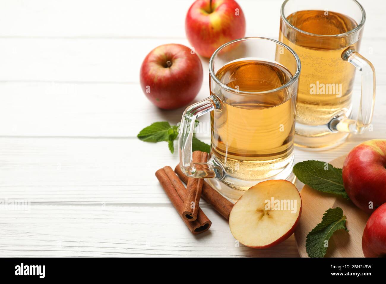 Composizione con sidro, cannella e mele su fondo di legno bianco Foto Stock