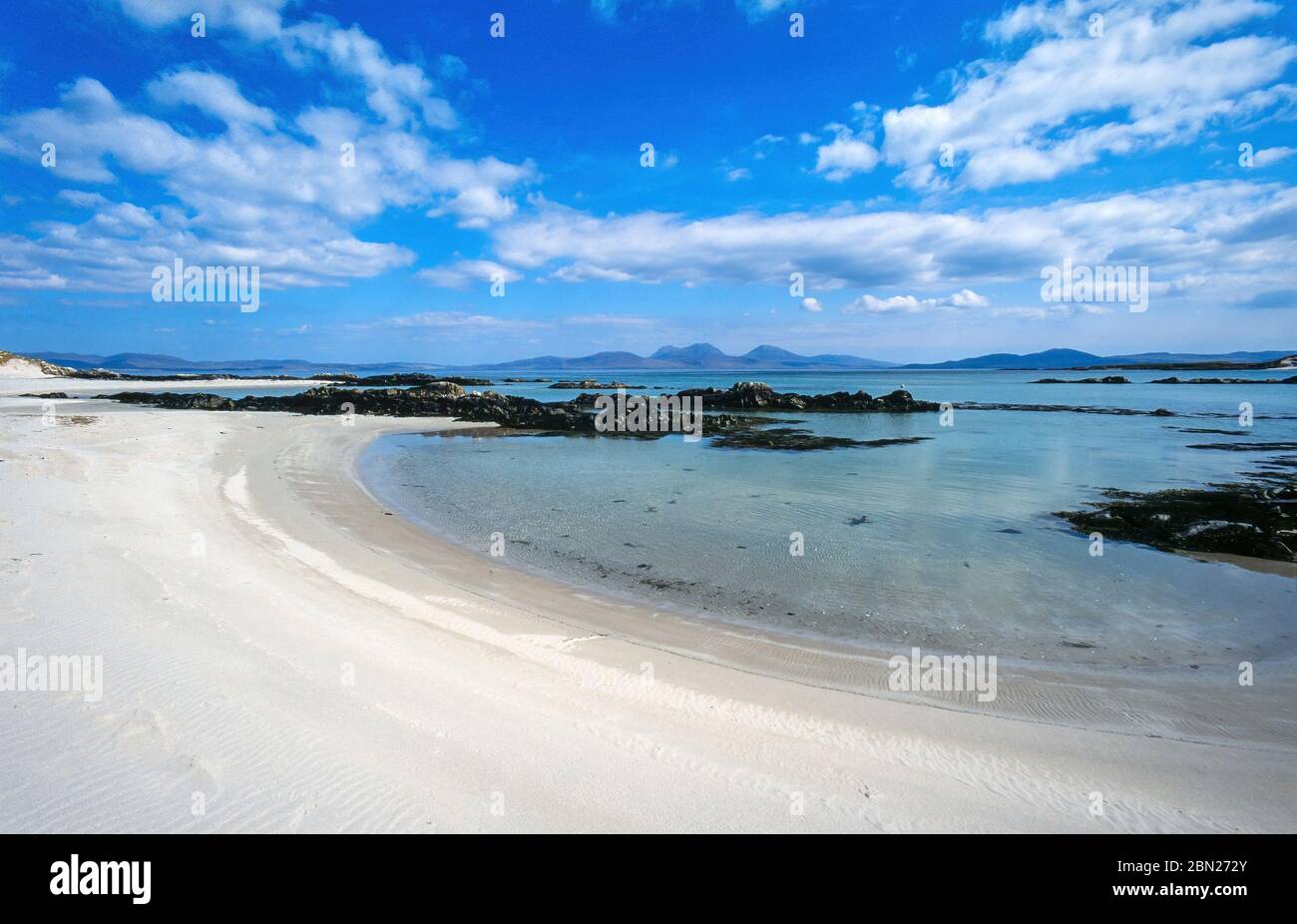 Vuota spiaggia di sabbia bianca vicino allo Strand sull'Isola Ebrida di Colonsay in estate con l'Isola e i Pap del Giura all'orizzonte, Scozia, Regno Unito Foto Stock