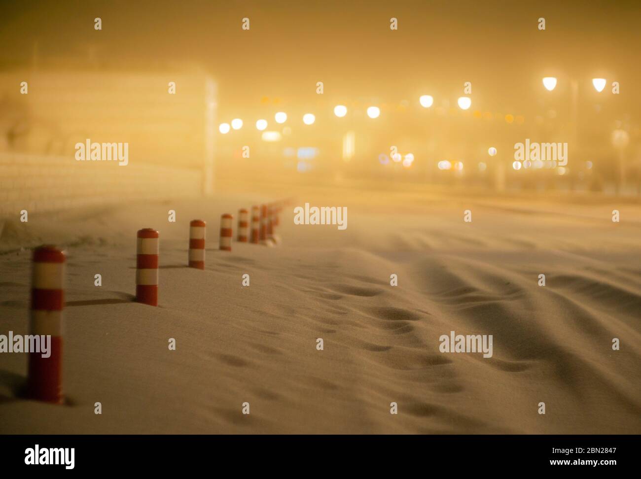 Tempesta di sabbia di notte che copre la strada con solo coni di traffico visibili Foto Stock