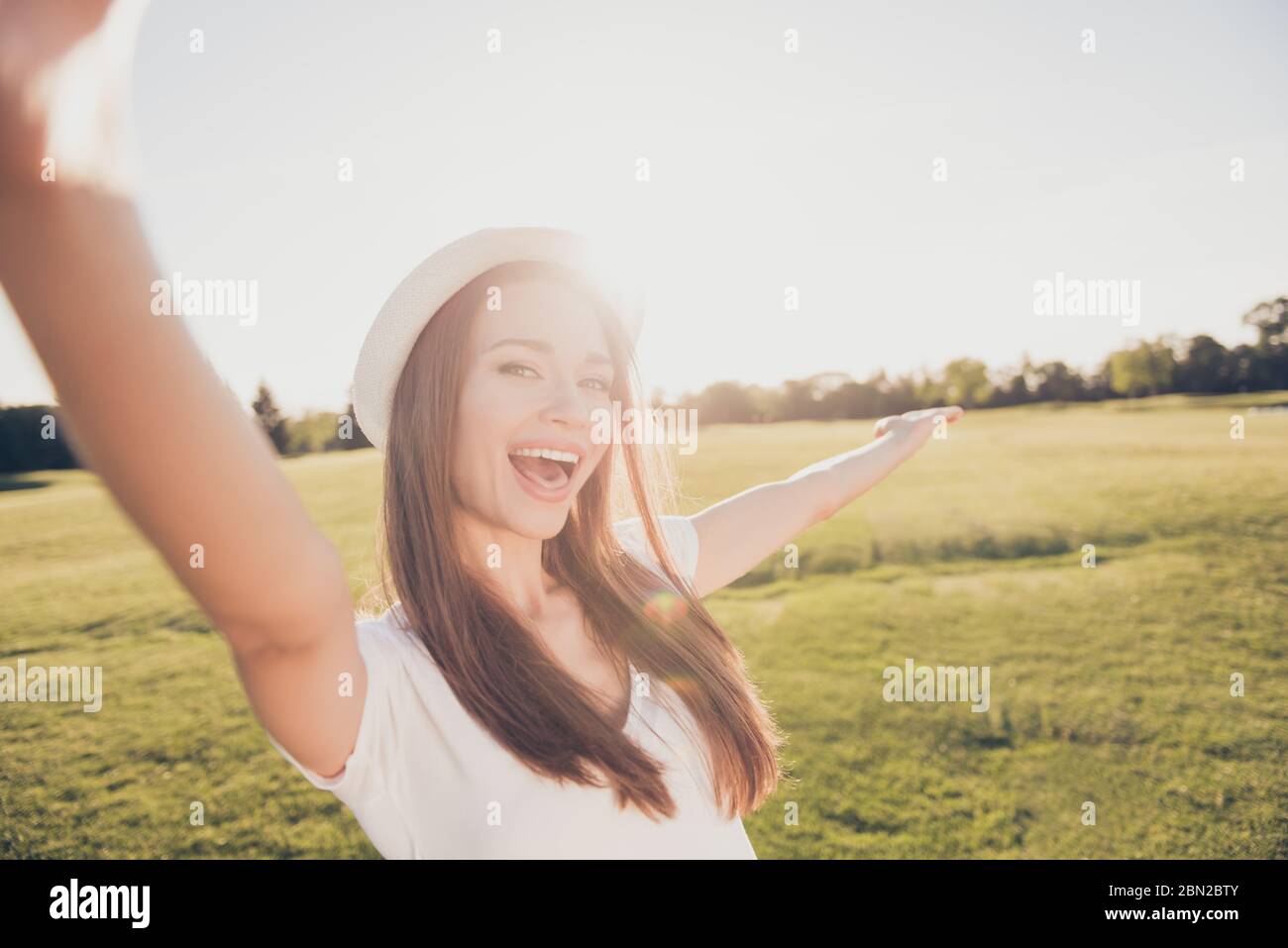 Atmosfera funky estate! Felice giovane ragazza in vacanza in un parco di primavera all'aperto sta facendo selfie, in un cappello elegante, indossando abiti casual, ridendo e. Foto Stock