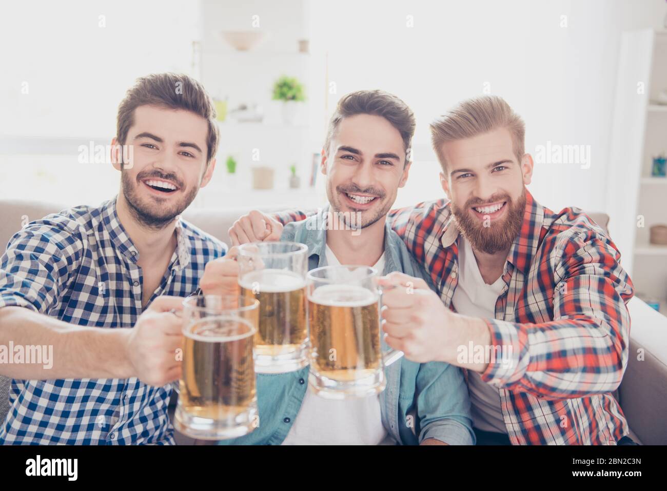 Uomini di Bachelor`s vita. Grazie! Primo piano foto di tre bei uomini che celebrano la vittoria e sorseggiano bicchieri di birra. Sono appassionati di sport Foto Stock