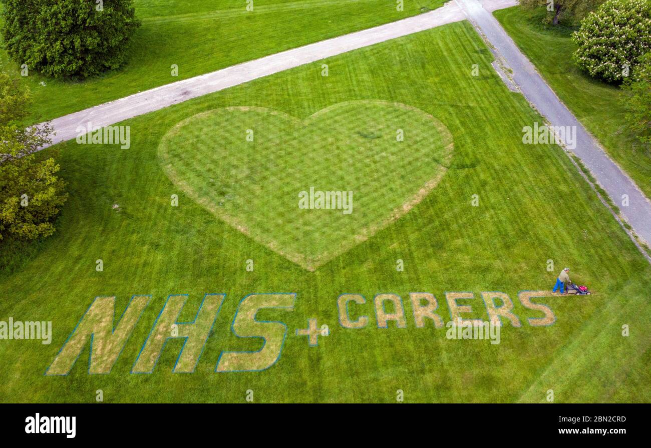 L'orticoltore di macchinari e di tappeti Turf Nigel Downs mette il tocco finale a un messaggio di ringraziamento per il personale e gli accompagnatori del NHS Hyde Hall Gardens a Chelmsford, Essex. Foto Stock