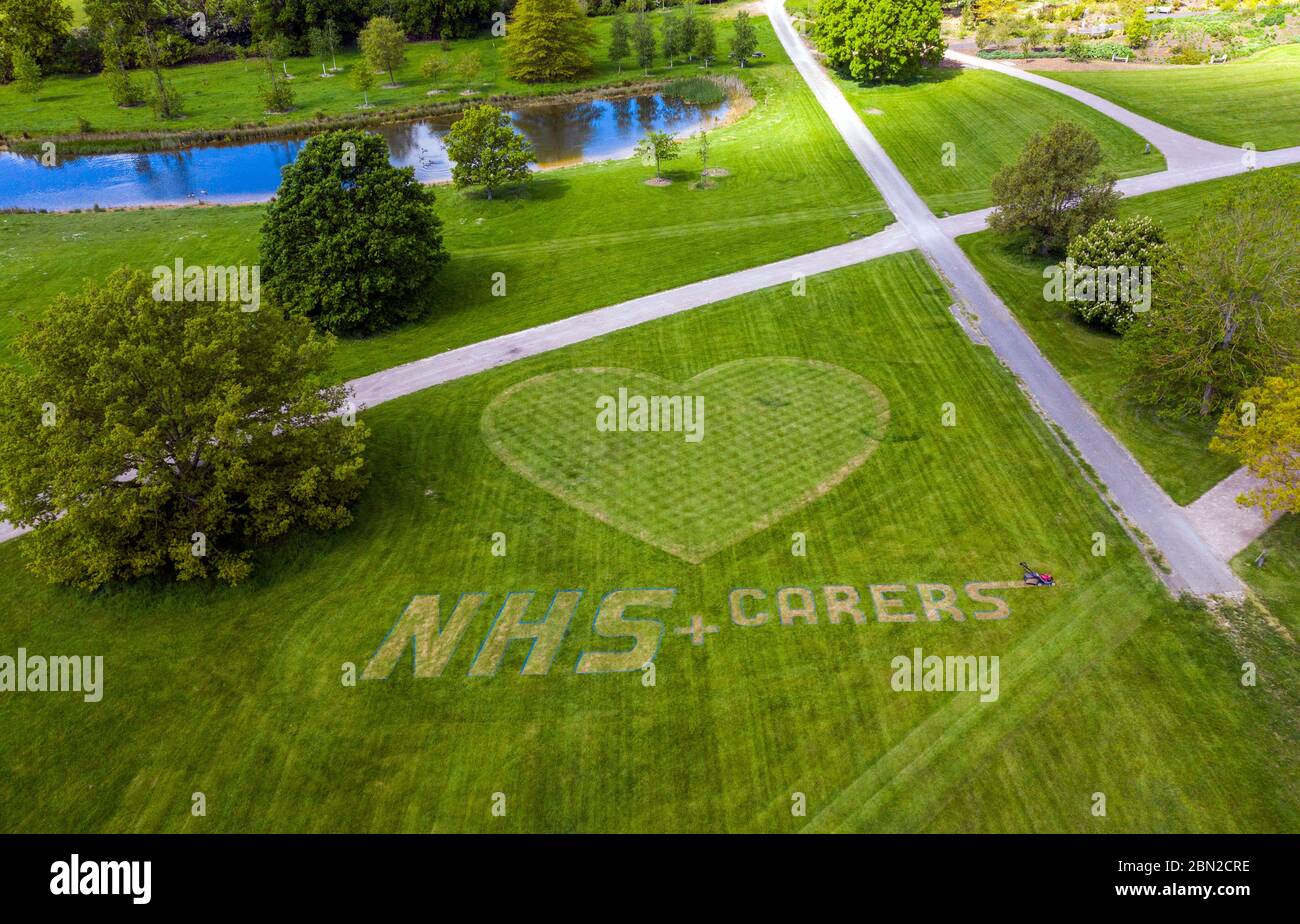 L'orticoltore di macchinari e di tappeti Turf Nigel Downs mette il tocco finale a un messaggio di ringraziamento per il personale e gli accompagnatori del NHS Hyde Hall Gardens a Chelmsford, Essex. Foto Stock