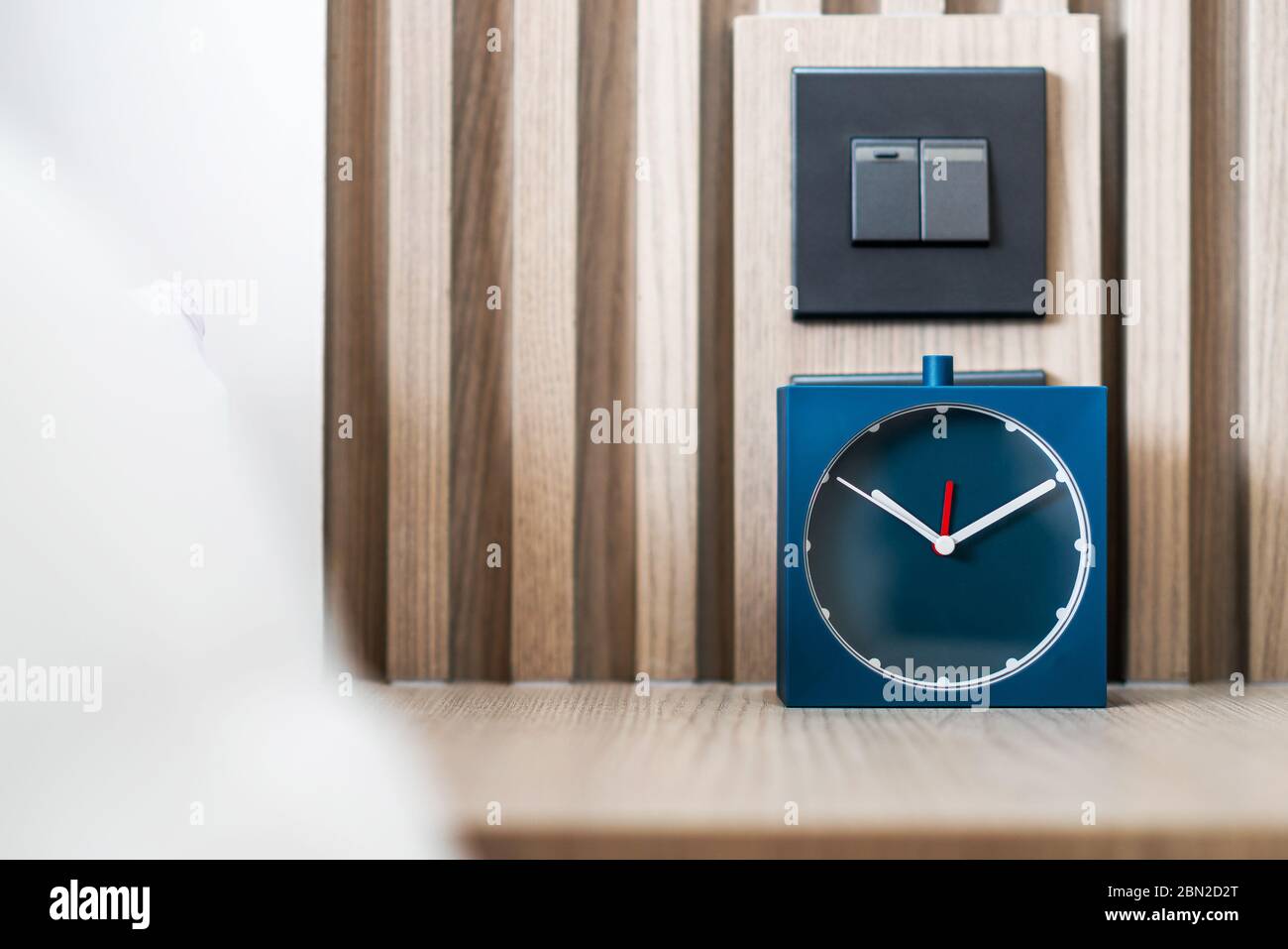 Sveglia analogica blu quadrata sul tavolo in camera da letto. Stile orologio minimo. Foto Stock