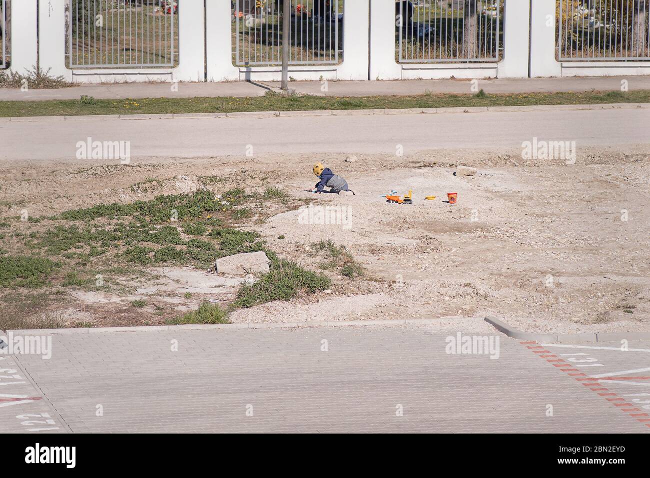 I bambini si siedono sulla strada e dipingono con i bastoni sul terreno. UN piccolo bambino gioca sulla strada a terra, i parchi giochi sono chiusi a causa del virus. Foto Stock