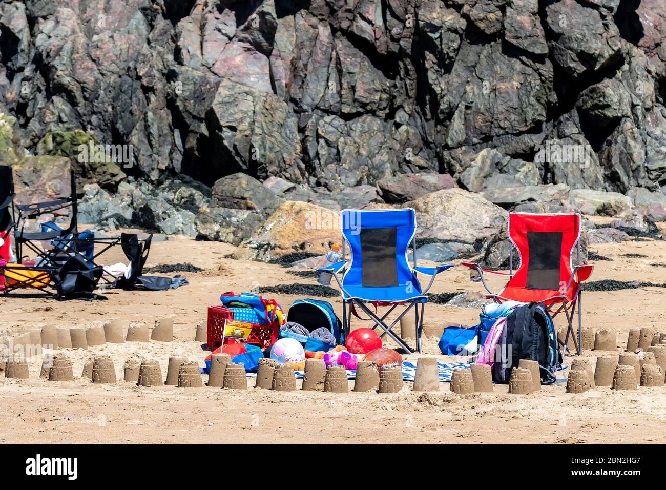 Due sedie da spiaggia, asciugamani, palle e altri oggetti correlati sulla spiaggia. È una giornata di sole. Foto Stock