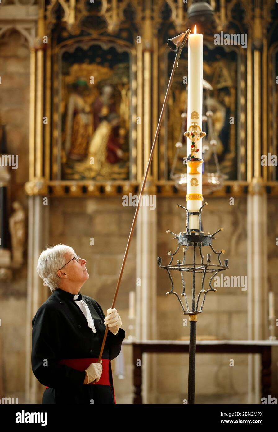Canon Maggie McLean, canonico missionario a York Minster, accende la candela pasquale come clero alla cattedrale ha lanciato una nuova iniziativa per utilizzare la candela come un fuoco per la preghiera per tutti coloro che sono colpiti dalla pandemia di Coronavirus. Foto Stock