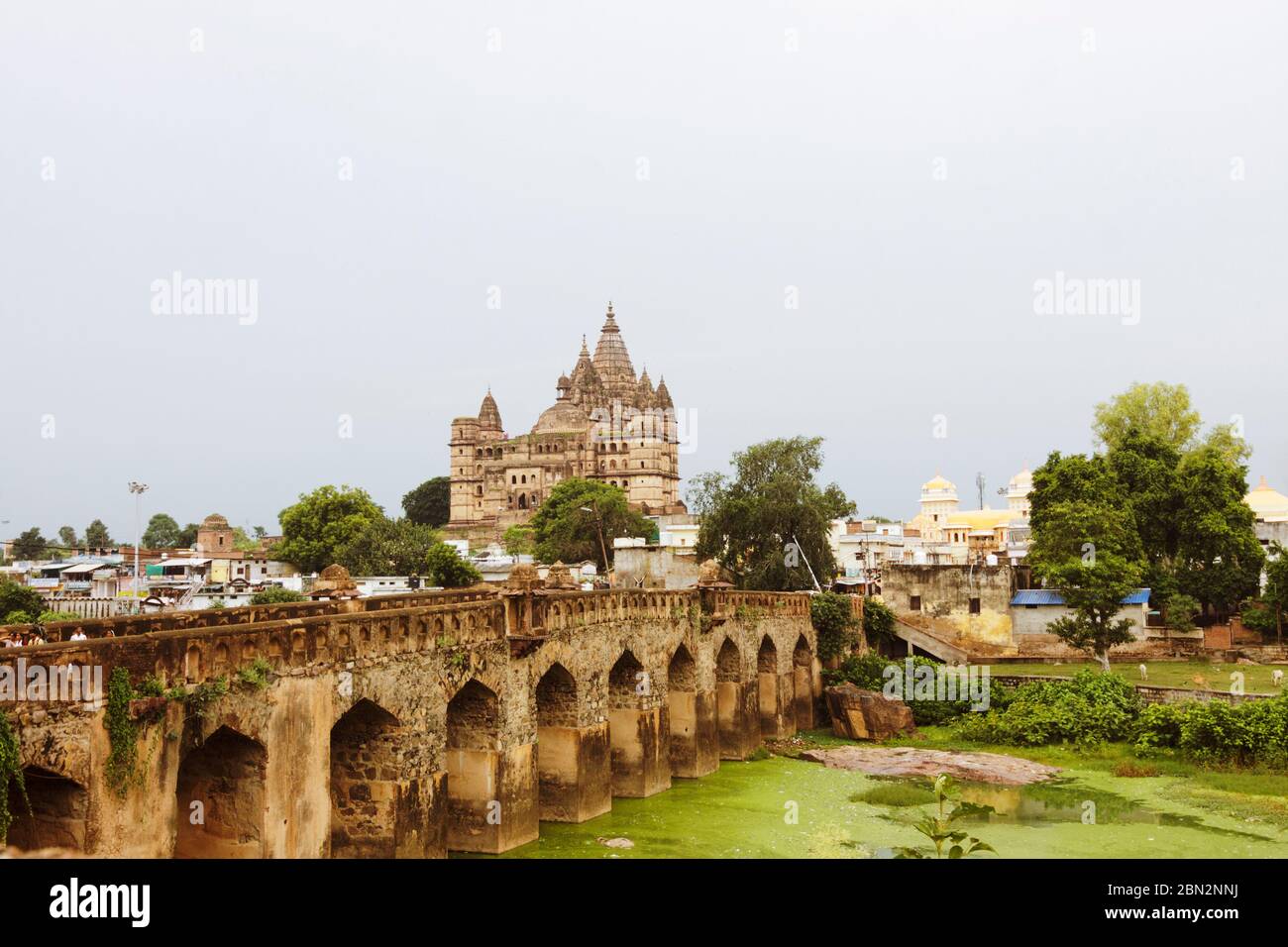 Orchha, Madhya Pradesh, India : ponte di Mughal sul fiume Betwa con il Tempio di Chaturbhuj sullo sfondo. Foto Stock