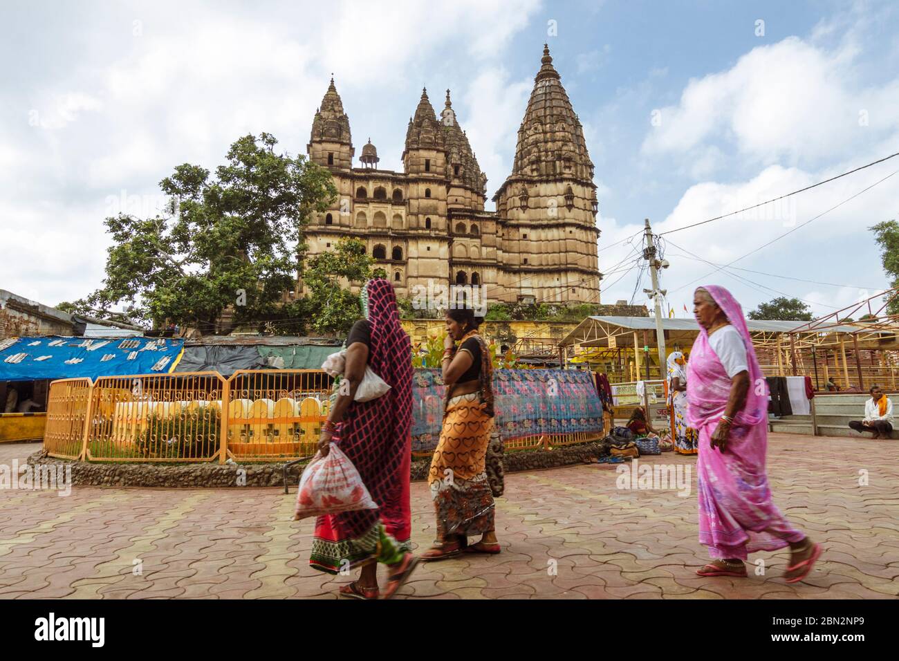 Orchha, Madhya Pradesh, India : tre donne camminano oltre il 9 ° secolo Chaturbhuj Tempio; s una struttura complessa multi-piano che mescola tempio, forte e. Foto Stock