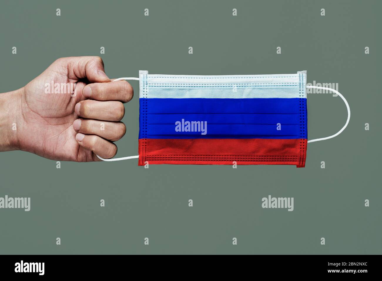 Primo piano di uomo con una maschera chirurgica modellata con la bandiera della Russia su uno sfondo grigio Foto Stock