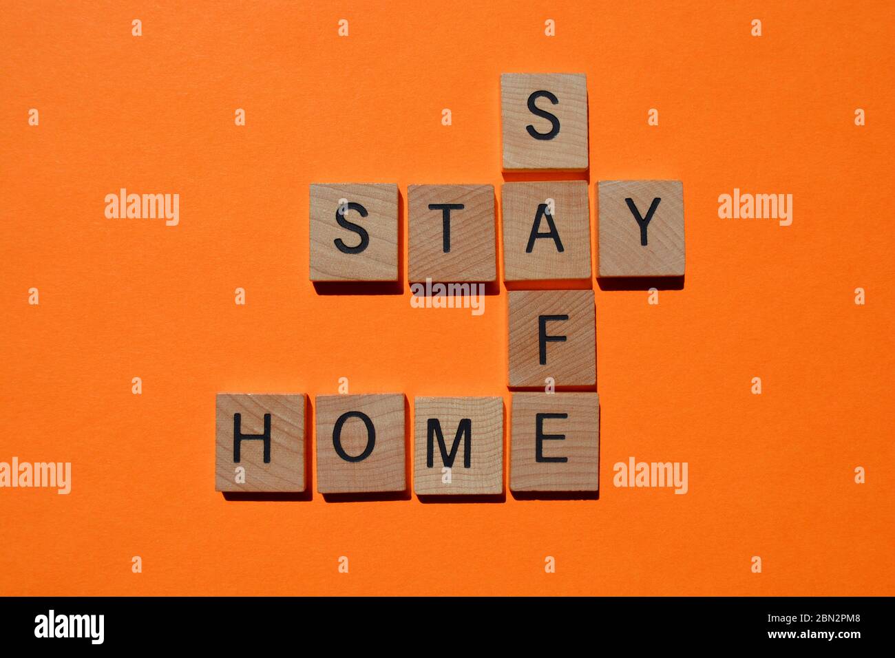 Soggiorno, Casa, sicuro, parole in lettere alfabetiche in legno in forma di crocetta isolato su sfondo arancione brillante Foto Stock