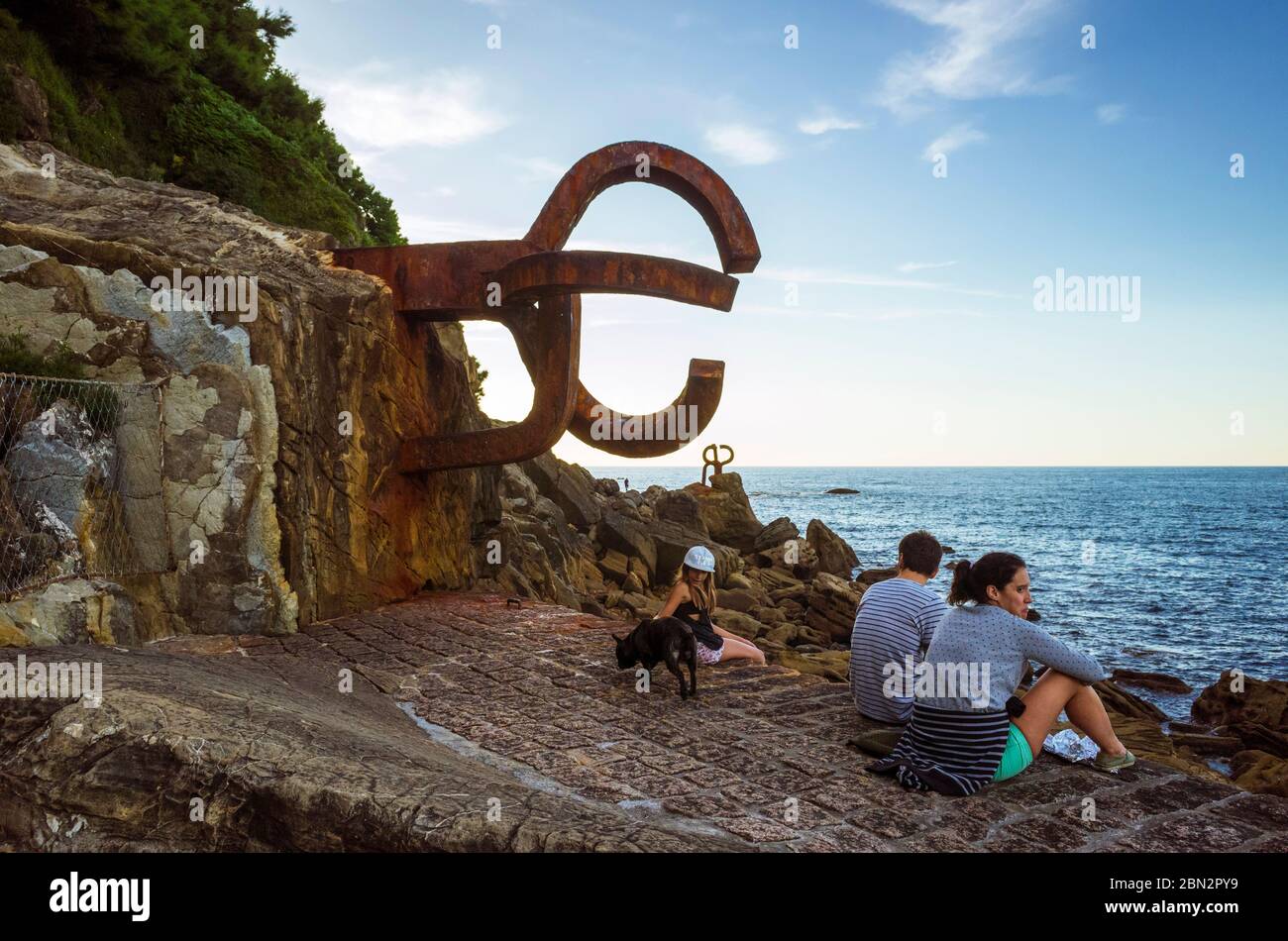 San Sebastian, Gipuzkoa, Paesi Baschi, Spagna : i visitatori siedono accanto al pettine del vento (Peine del viento/Haizearen orrazia) scultura Foto Stock