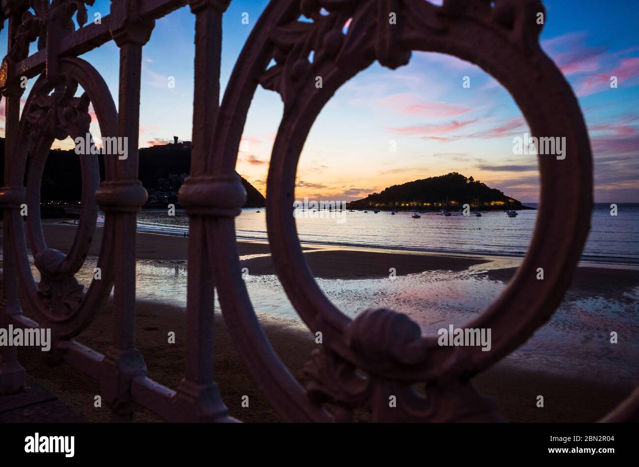 San Sebastian, Gipuzkoa, Paesi Baschi, Spagna : la Concha spiaggia al tramonto come visto attraverso il banister iconico. Foto Stock