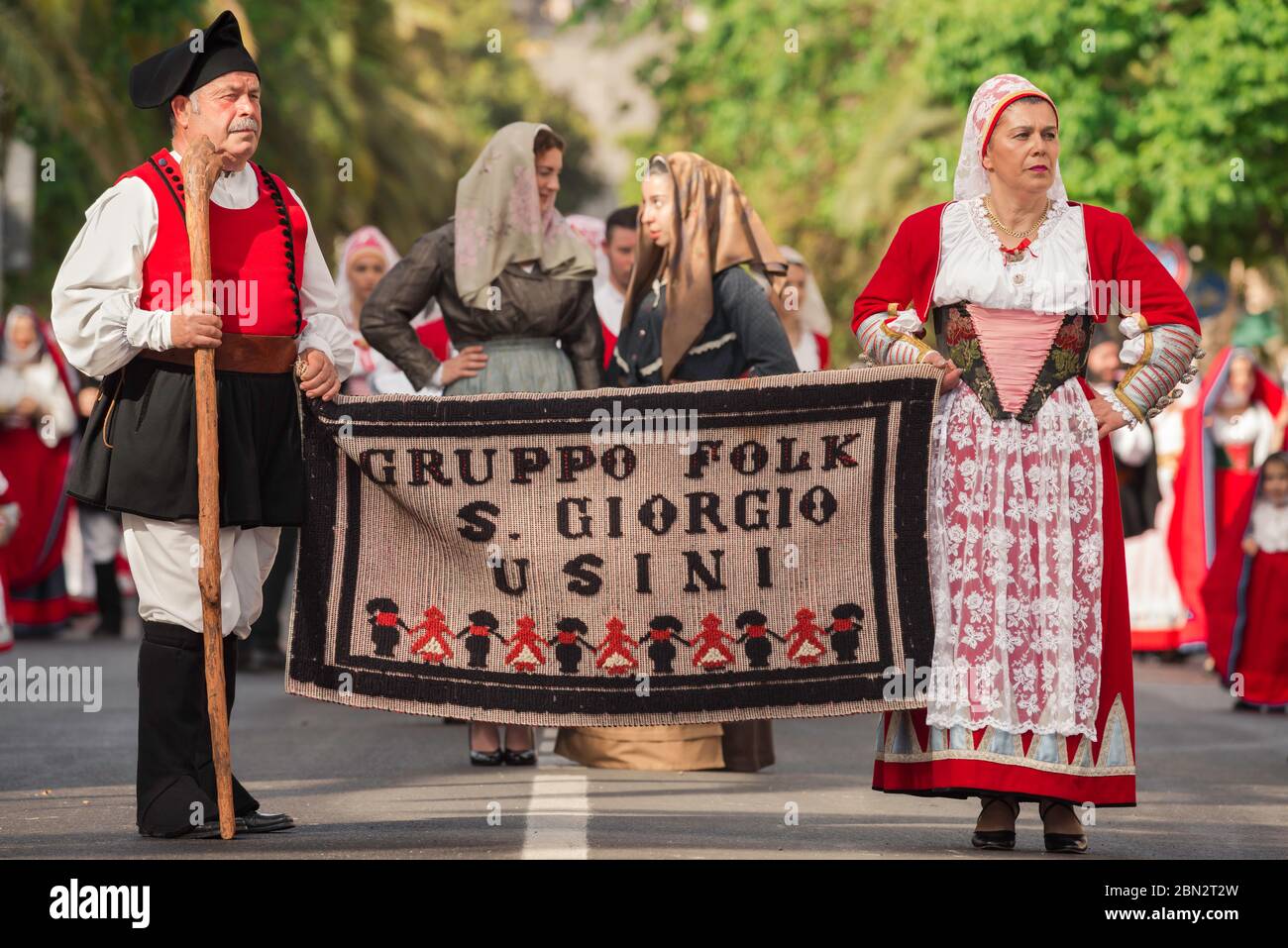 Sardegna sagra tradizionale, una coppia di mezza età in costume tradizionale portano il loro banner locale nella Cavalcata festival processione, Sassari. Foto Stock