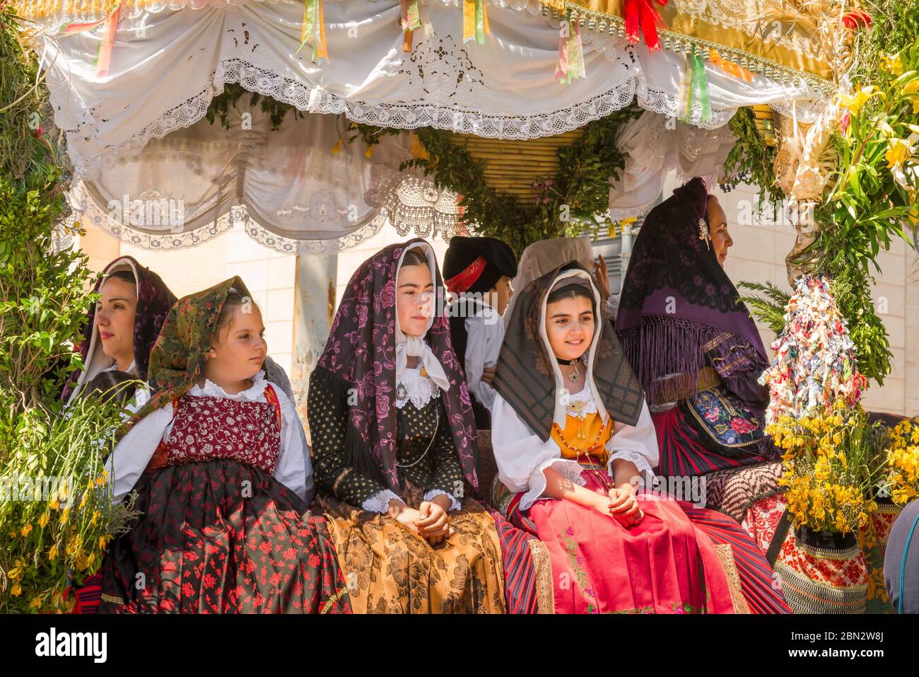 Sardegna festa della gente bambini, tre ragazze in abito tradizionale cavalcano un galleggiante decorato durante la processione Cavalcata festival, Sassari, Sardegna Foto Stock