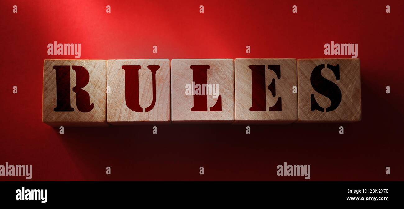 Parola di regole su cubi di legno su sfondo rosso. Norme, politiche e procedure concetto di legge Foto Stock