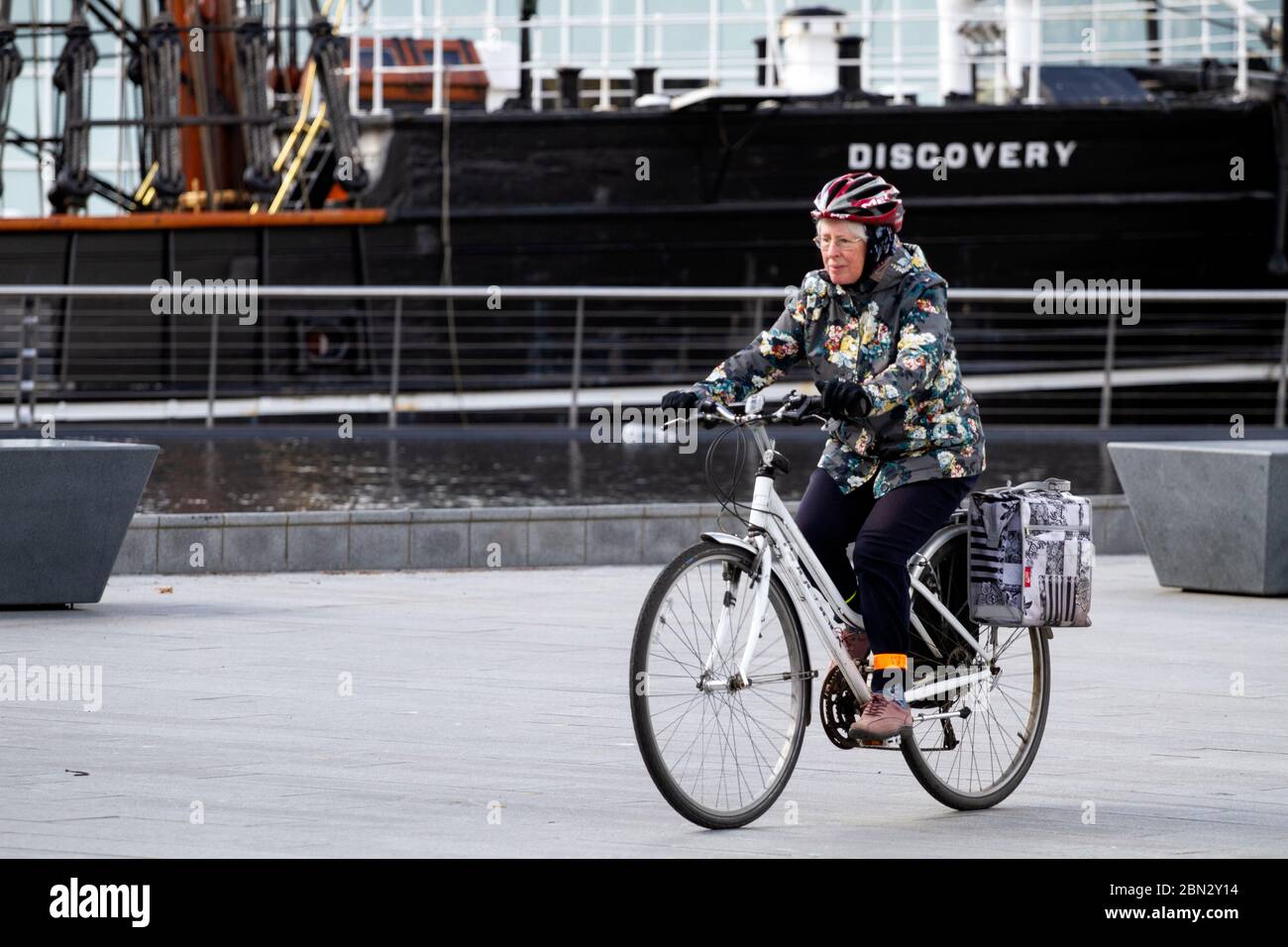 Dundee, Tayside, Scozia, Regno Unito. 12 maggio 2020. Tempo nel Regno Unito: Una giornata di sole e nuvoloso con incantesimi a Dundee Scozia con temperatura massima 12°C.. Una donna anziana che gode del clima fresco mentre prende le esercitazioni esterne leggere che cavalcano la sua bicicletta di Ridgeback oltre la nave di scoperta di RRS lungo il lungomare durante le limitazioni di bloccaggio di Covid-19. Credit: Dundee Photographics/Alamy Live News Foto Stock