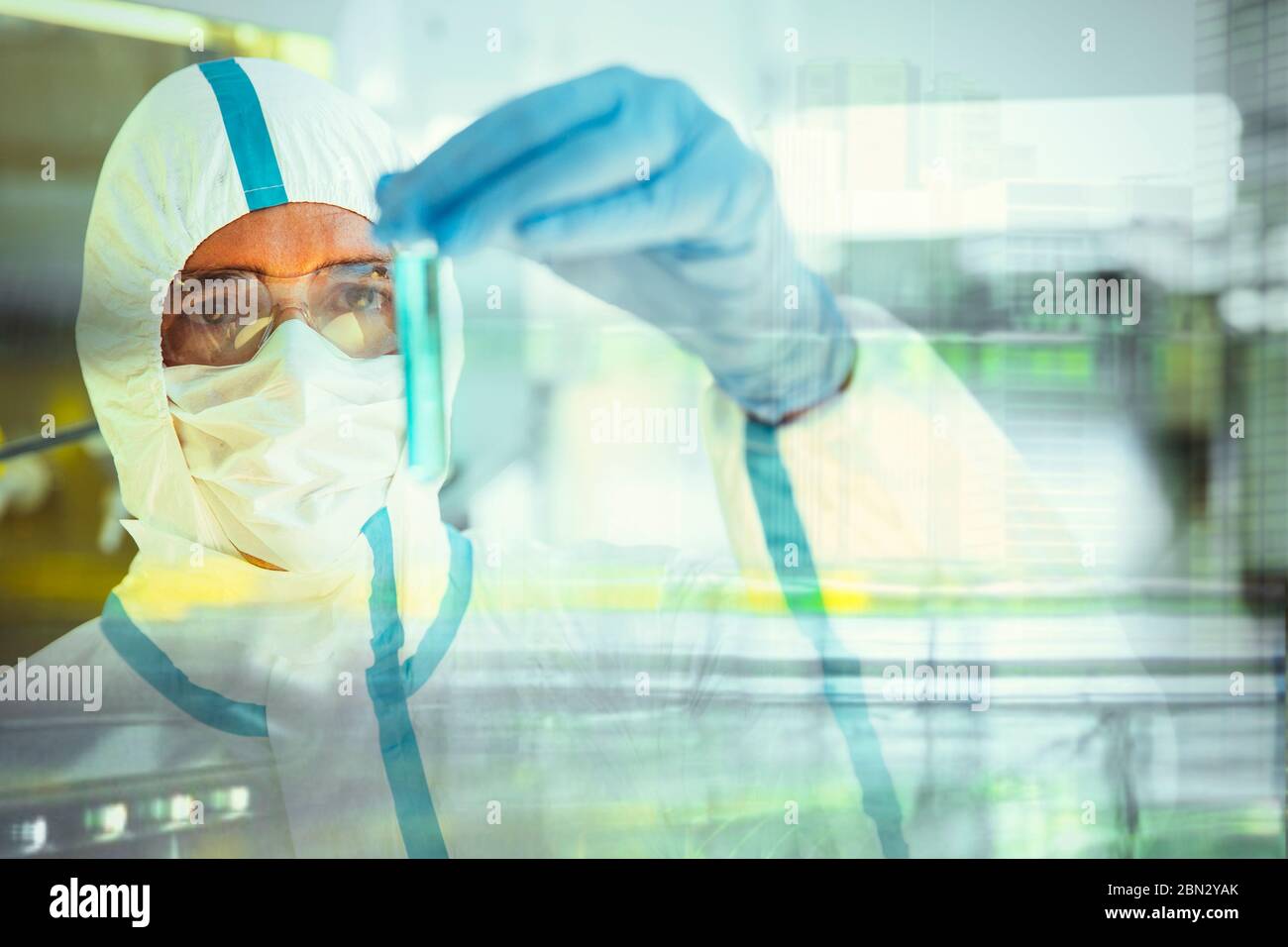 Scienziato maschile in tuta pulita studiando fiala in laboratorio Foto Stock