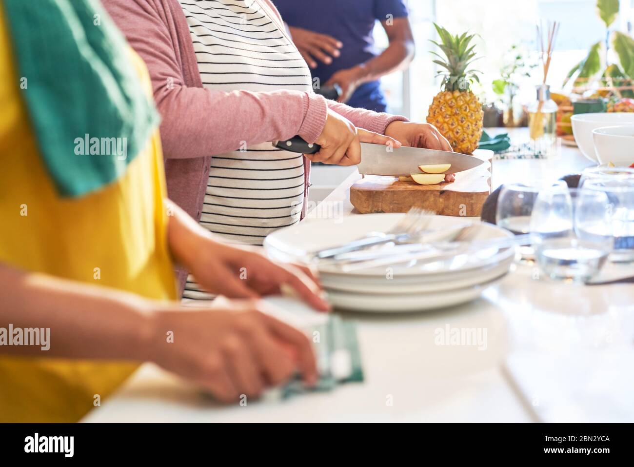 Amici che tagliano frutta fresca in cucina Foto Stock