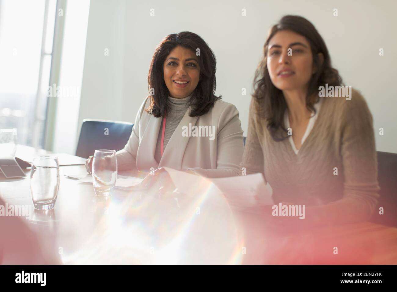 Donne d'affari che ascoltano nella soleggiata sala conferenze Foto Stock