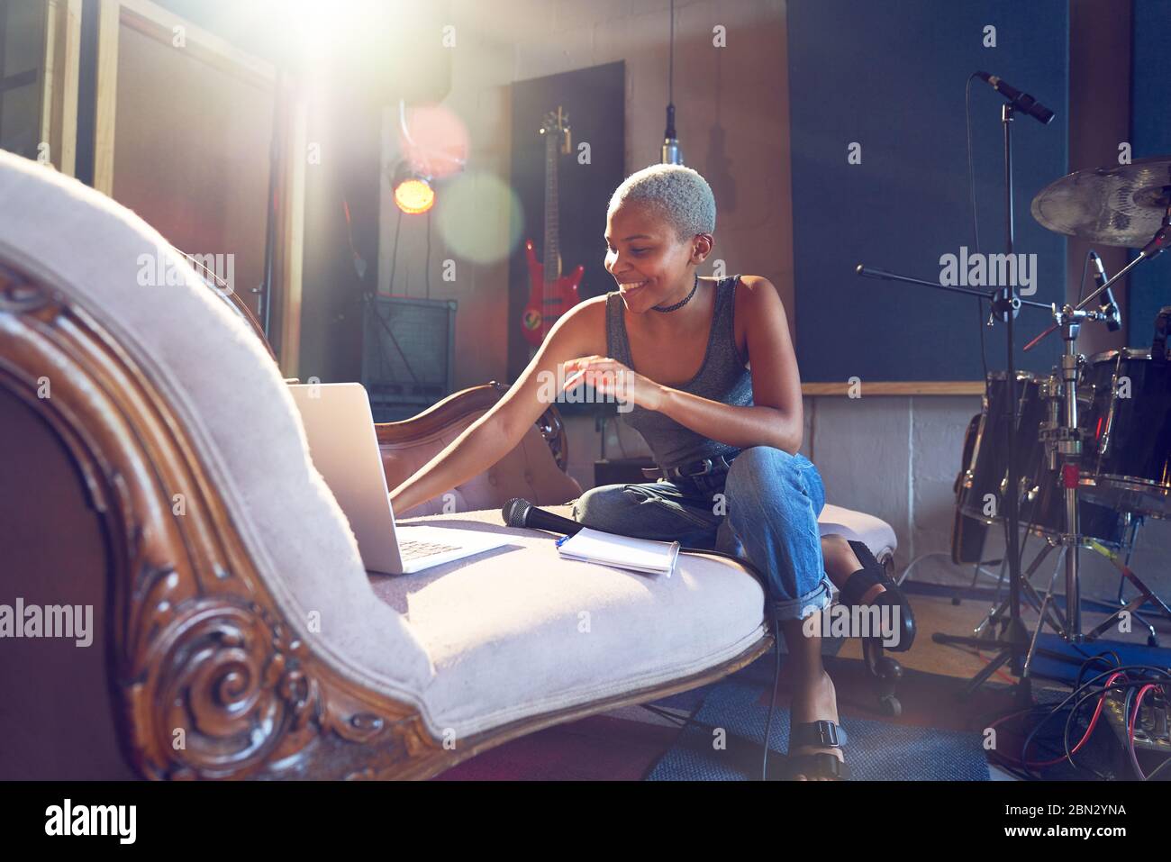 Smiling donna musicista canzone scrivere al portatile in studio di registrazione Foto Stock