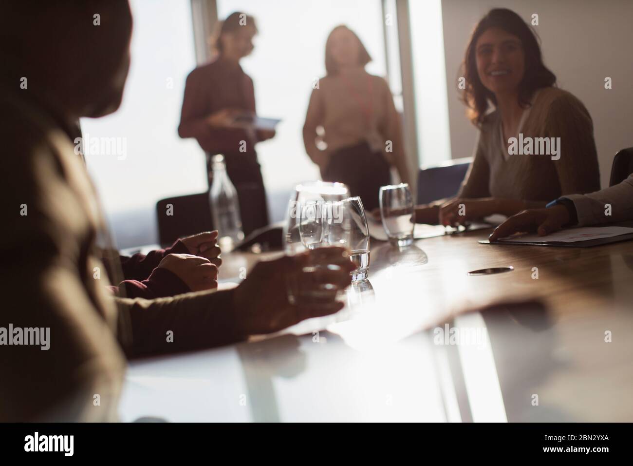 Uomini d'affari che parlano in una soleggiata sala conferenze Foto Stock
