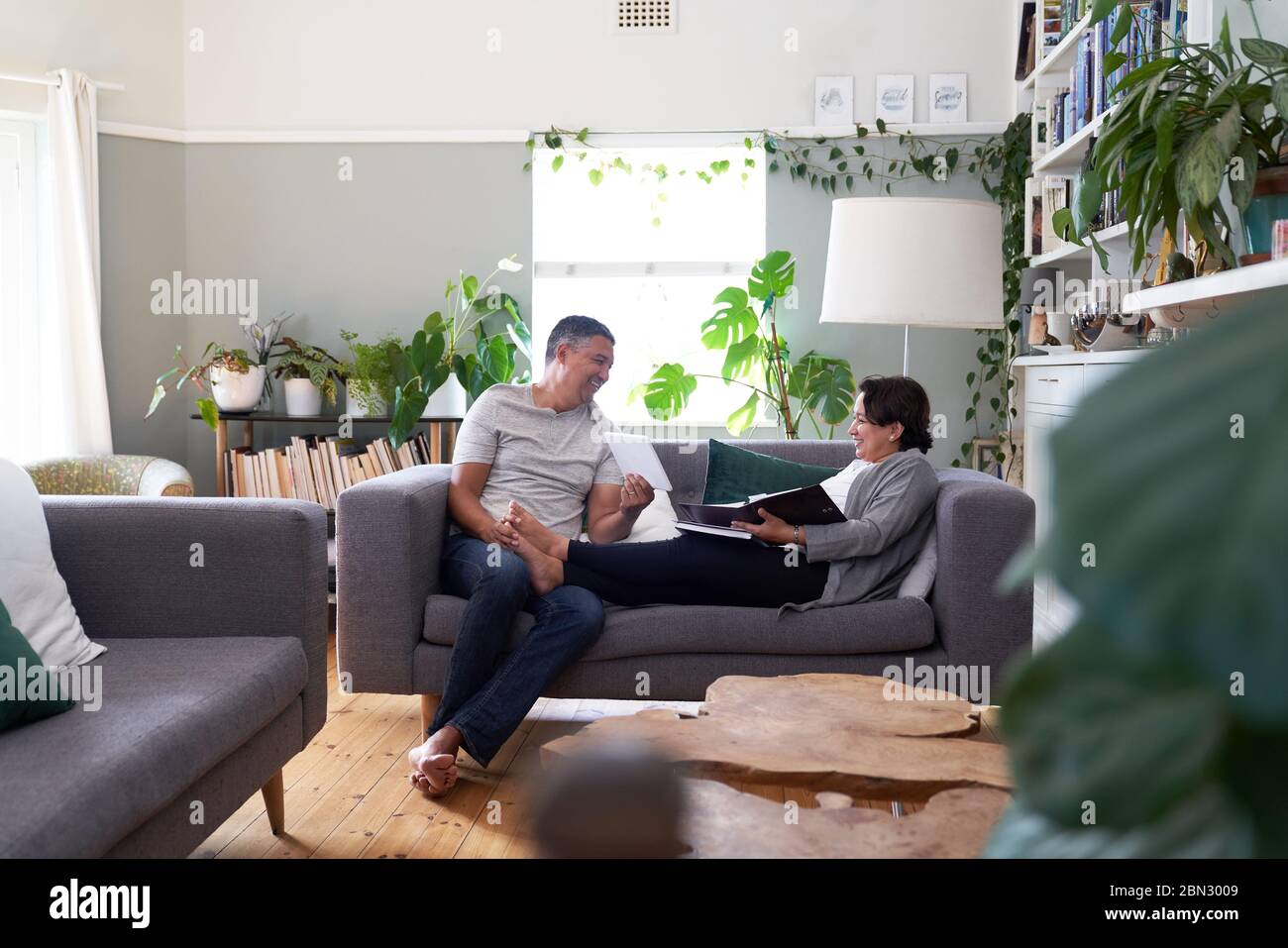 Felice coppia matura che usa un tablet digitale sul divano del soggiorno Foto Stock