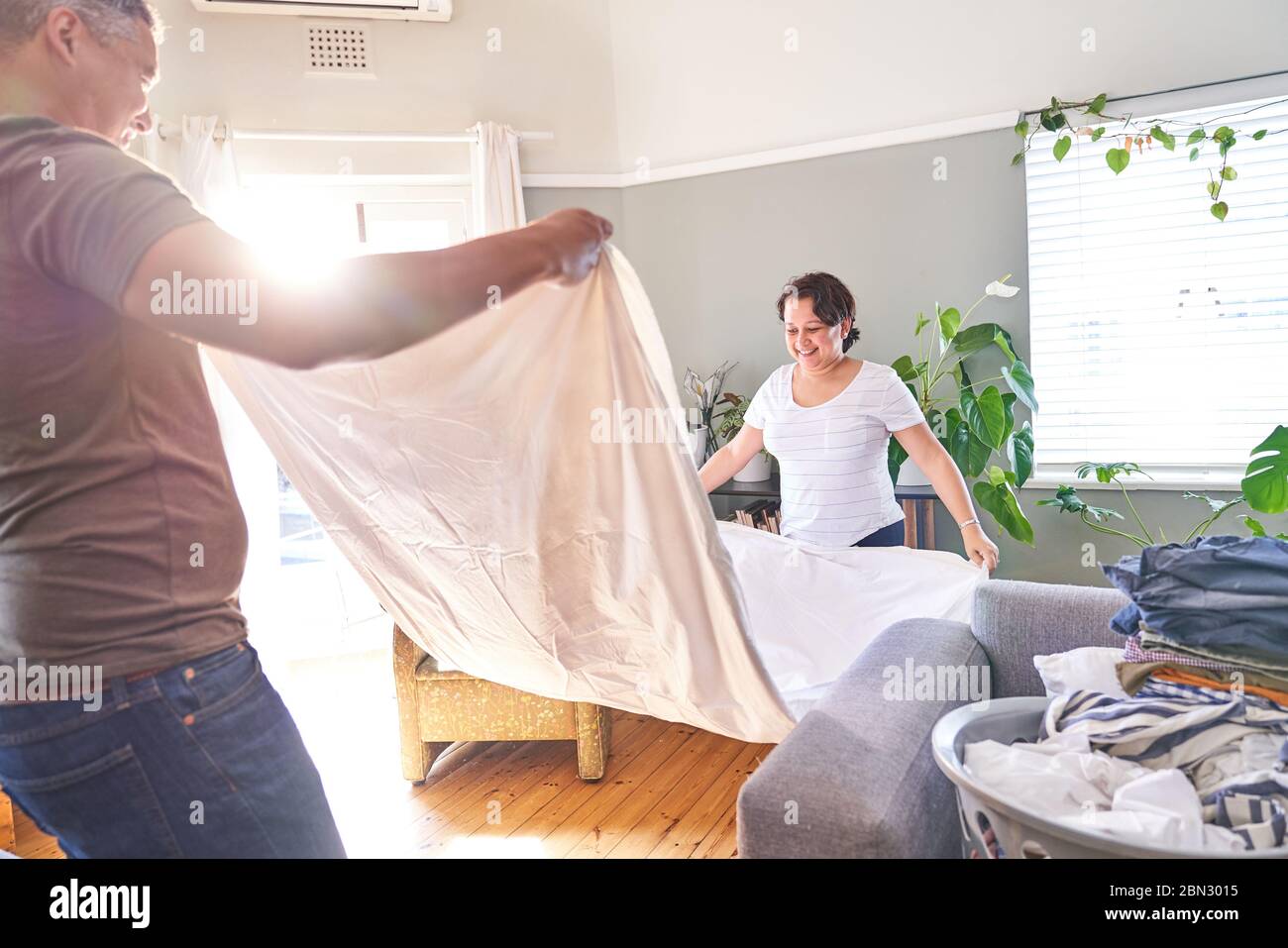 Sorridente coppia matura fogli pieghevoli in un luminoso soggiorno Foto Stock