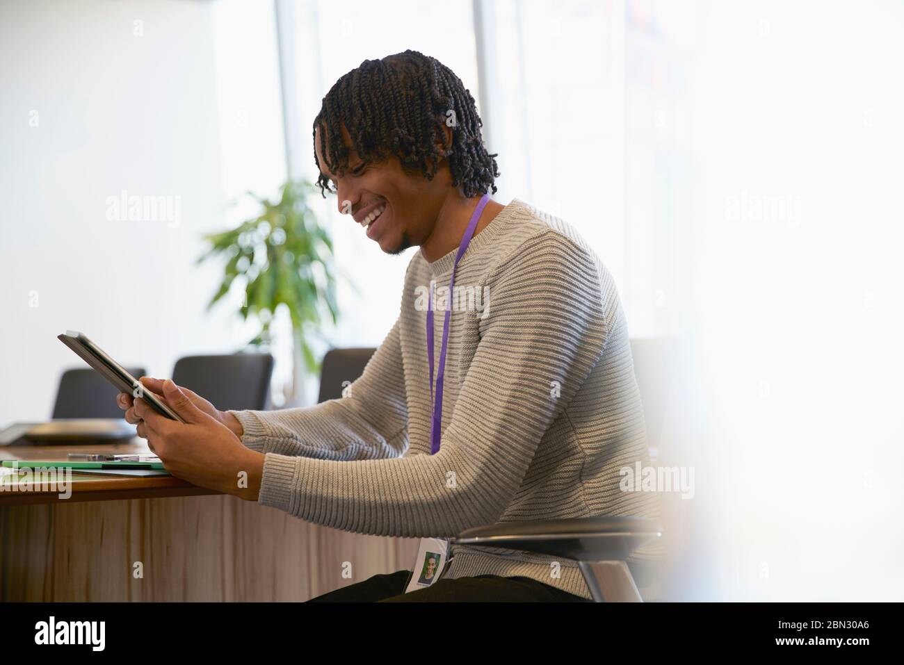 Imprenditore sorridente con tavoletta digitale in ufficio Foto Stock