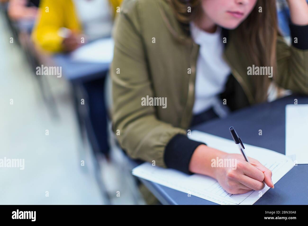 Studente di ragazza di scuola superiore che prende l'esame alla scrivania Foto Stock