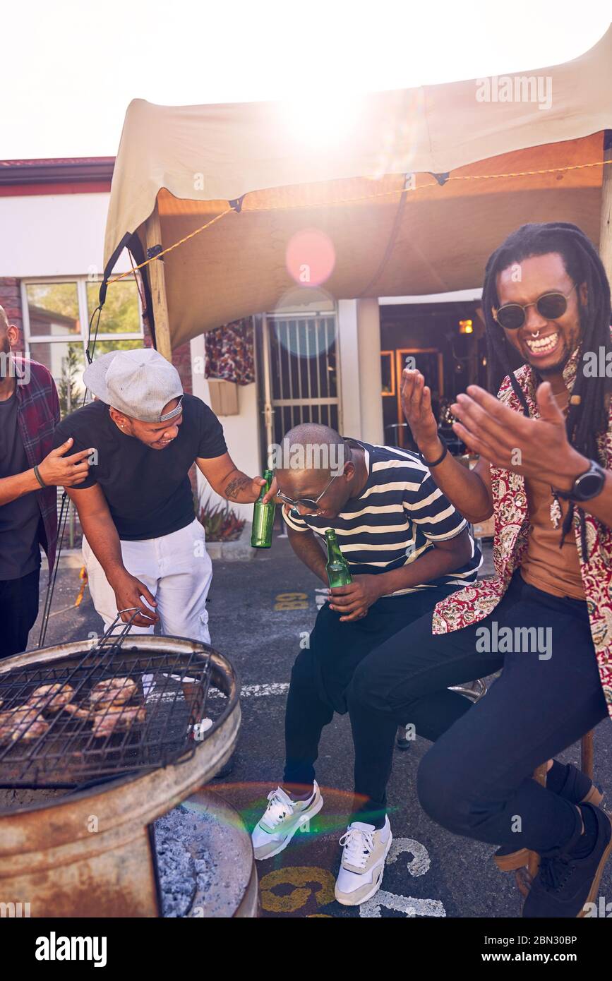 Felici amici che barbecue nel parcheggio soleggiato Foto Stock