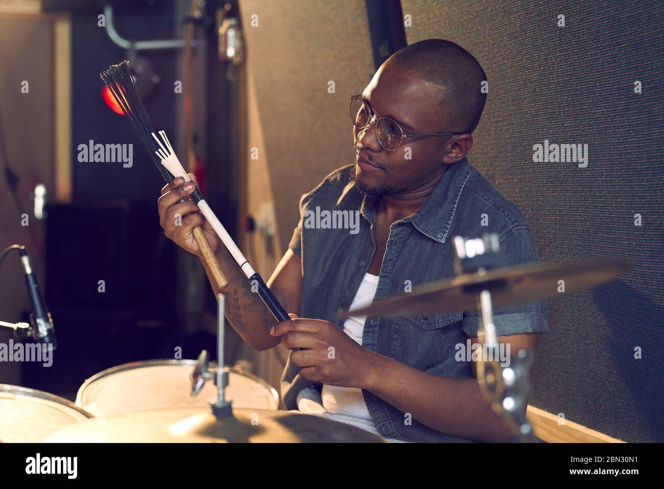 Batterista maschile con spazzola a tamburo in studio di registrazione Foto Stock