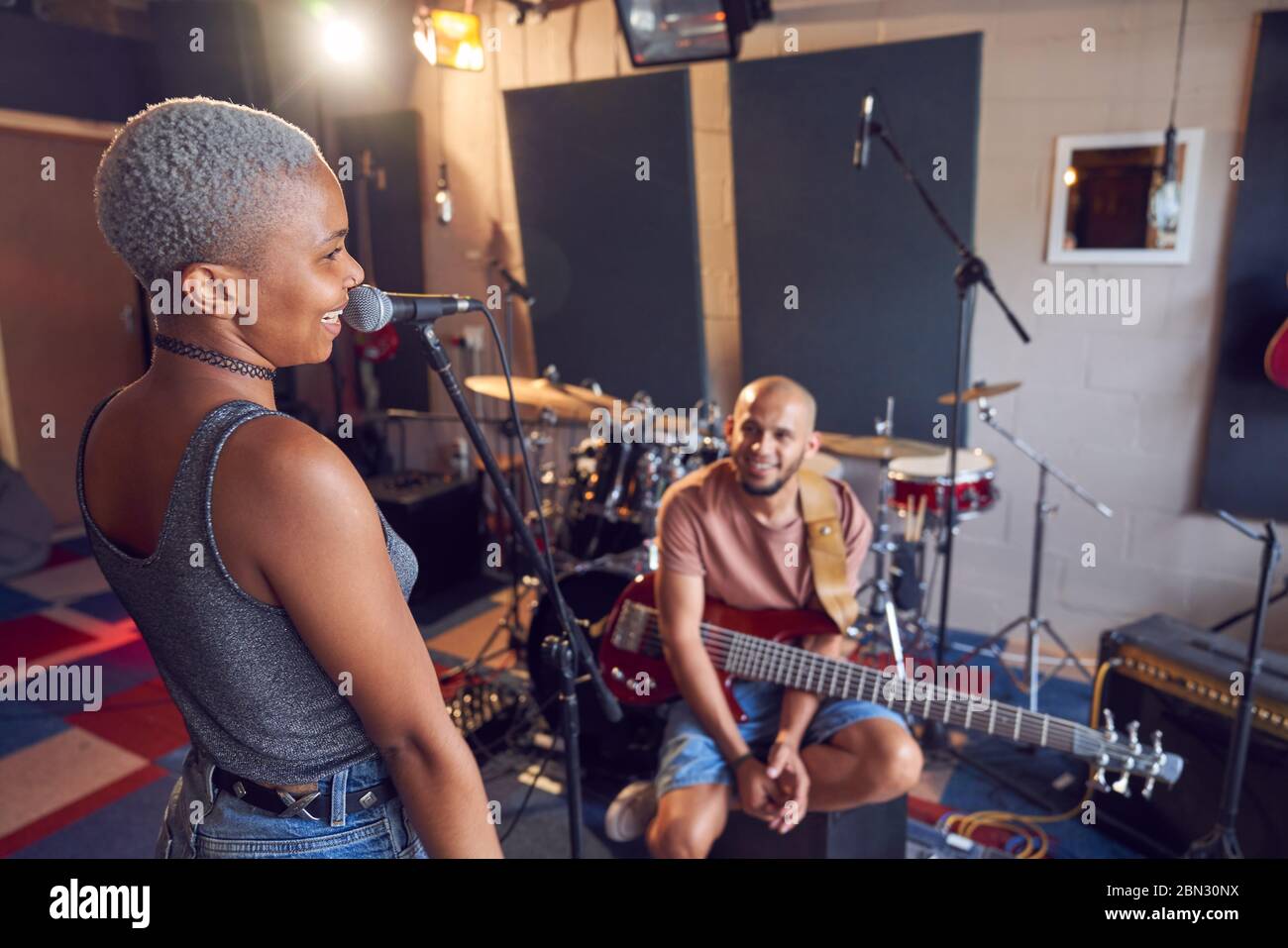 Musicisti sorridenti che praticano in studio di registrazione Foto Stock