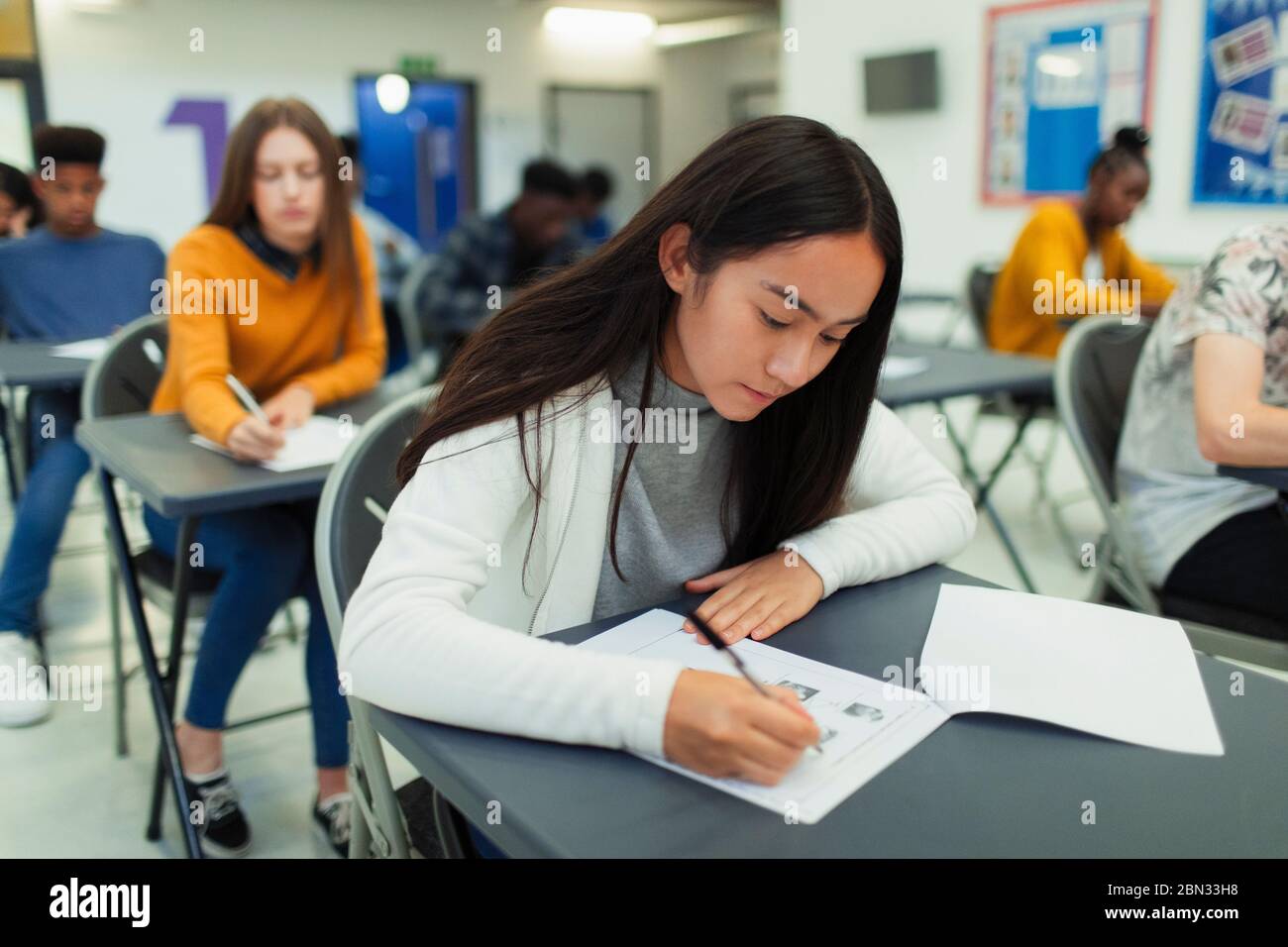 Studente di ragazze di scuola superiore che si occupa di esami alla scrivania in classe Foto Stock