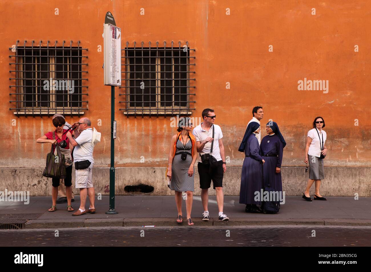 La gente aspetta alla fermata dell'autobus nel centro di Roma Foto Stock