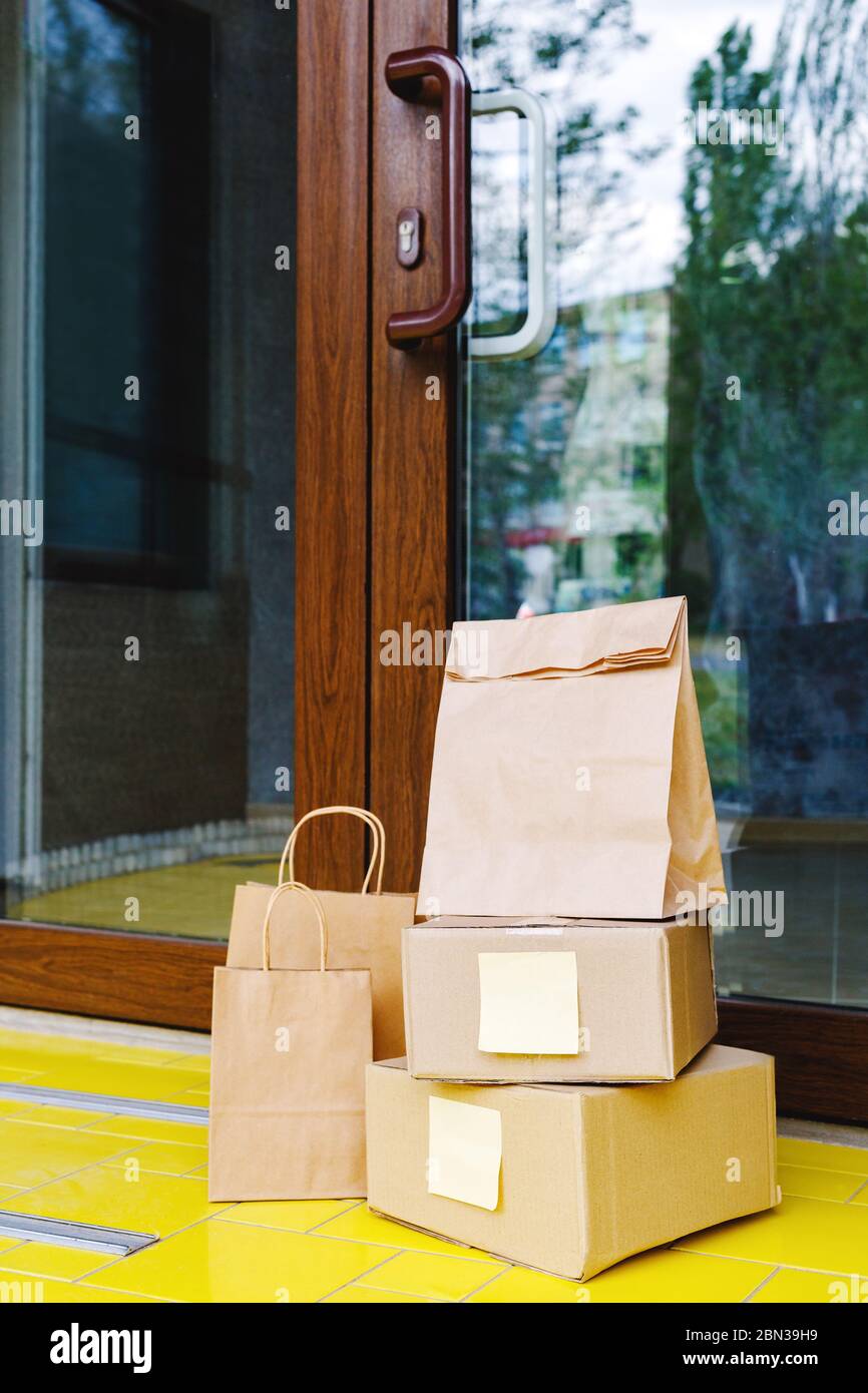 Scatole di consegna, sacchetti di carta sul portello vicino alla porta domestica. Consegna senza contatto. Shopping sicuro e-commerce acquisto pacchi a casa. Scatole consegnate a. Foto Stock