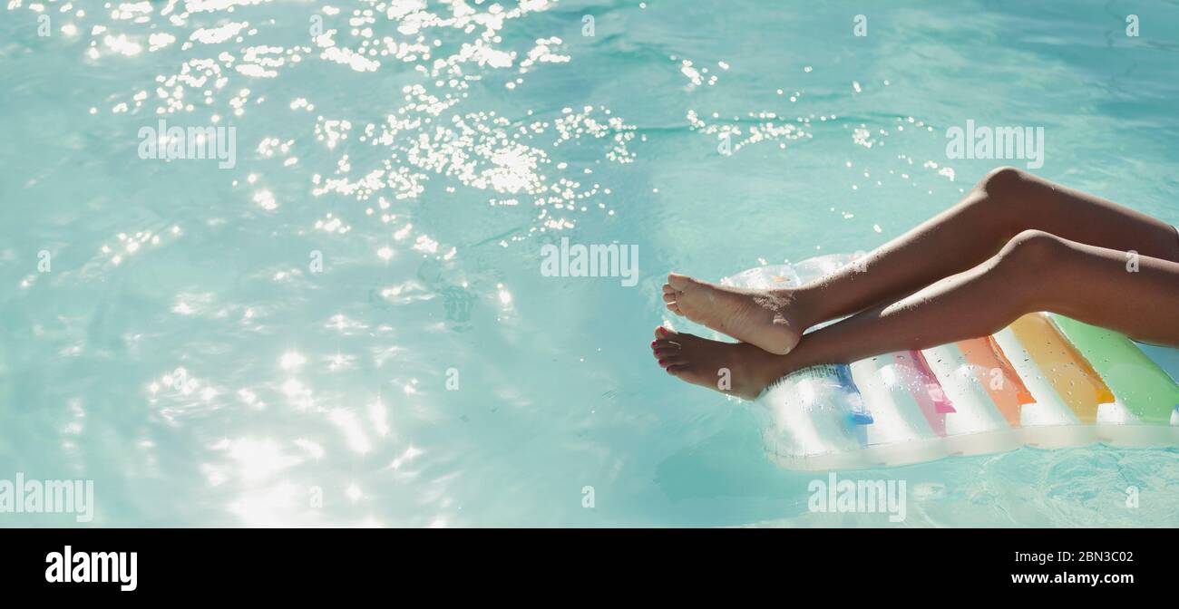 Giovane donna spensierata su una zattera in piscina soleggiata e tranquilla Foto Stock