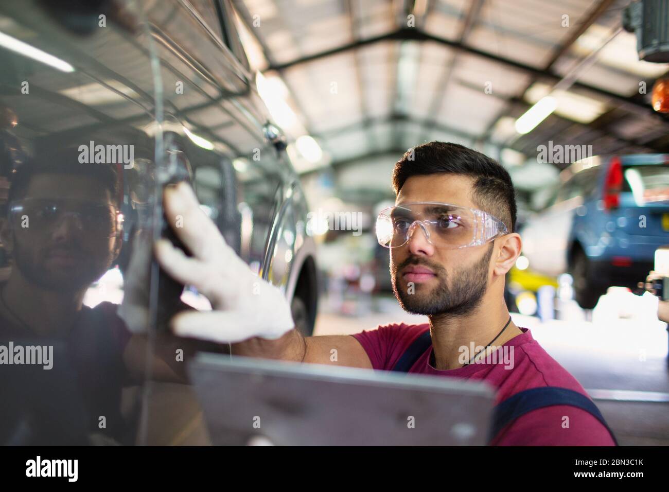 Meccanico maschile focalizzato utilizzando tablet digitale in officina di riparazione auto Foto Stock
