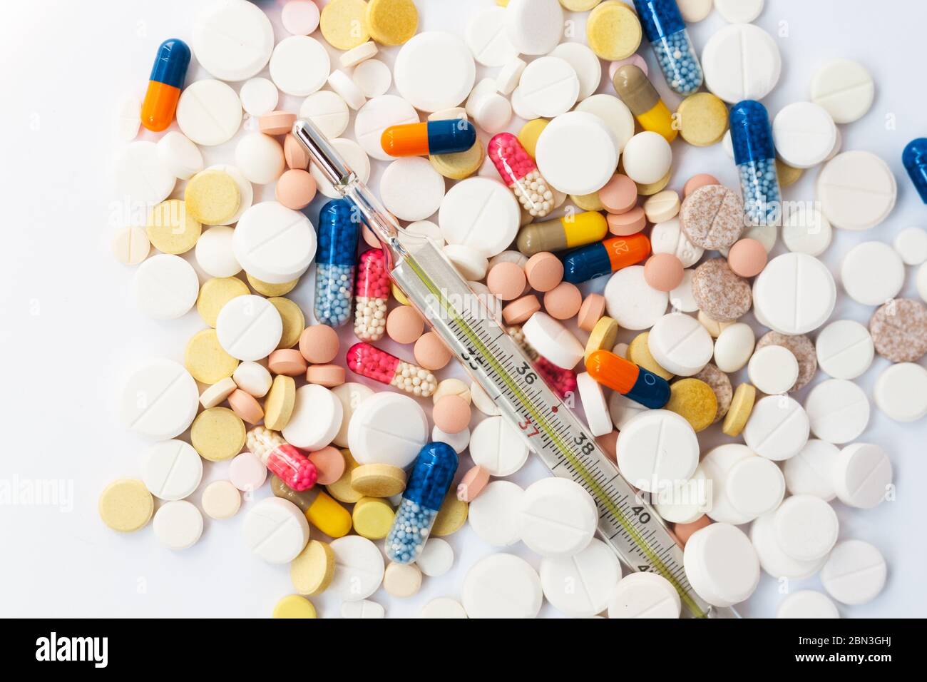 Termometro e pillole, medicina per polmonite, antibiotici su sfondo rosa. Coronavirus, MERS-cov, coronavirus Wuhan 2019-nCoV, concetto di Corona Foto Stock