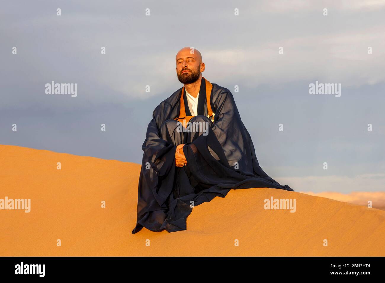Maestro Zen seduto su una duna nel deserto del Sahara, Marocco. Foto Stock