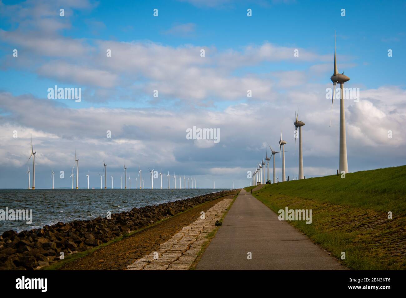 Percorso dalla diga verso l'enorme parco di mulini a vento con grandi turbine nei Paesi Bassi Noordoostpolder, parco di mulini a vento a energia verde a Flevoland Foto Stock