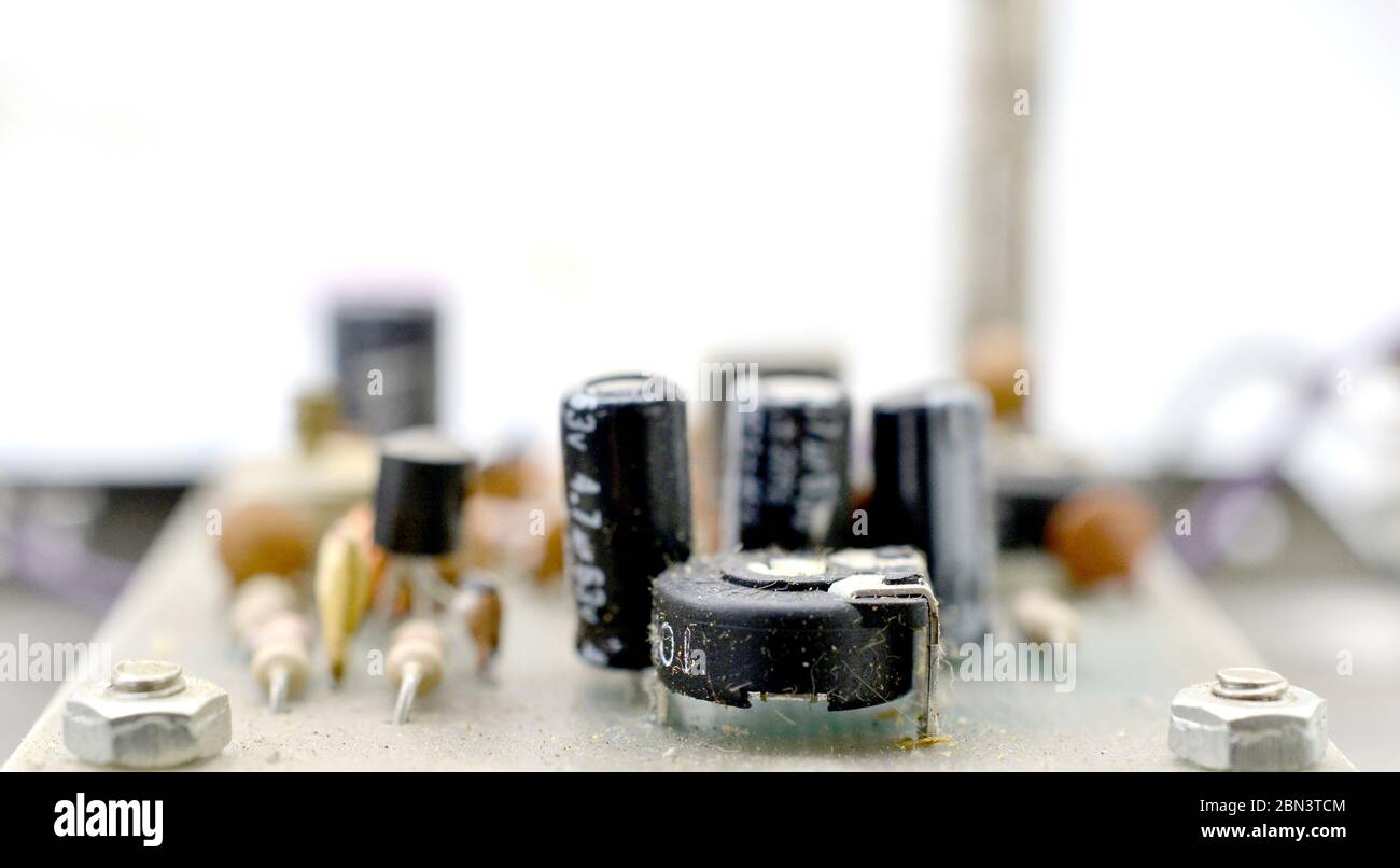 Sfondo di elettronica vintage polveroso e sporco con resistenze, condensatori, diodi e altri componenti. Foto Stock