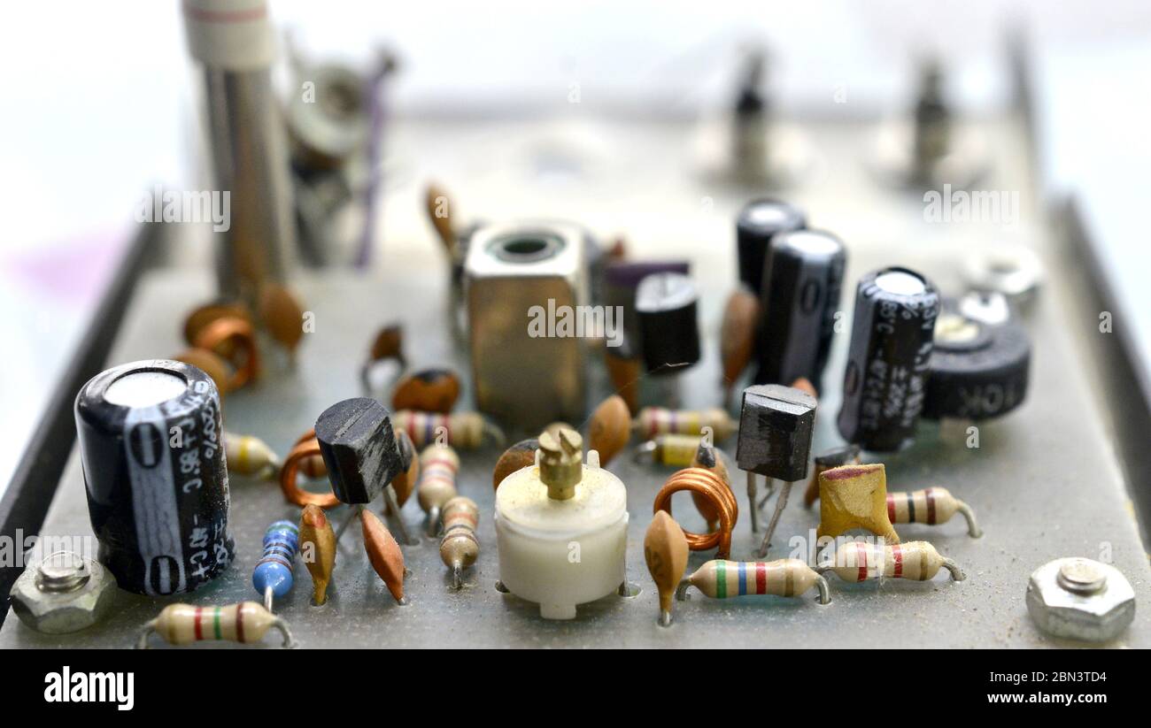 Sfondo di elettronica vintage polveroso e sporco con resistenze, condensatori, diodi e altri componenti. Foto Stock