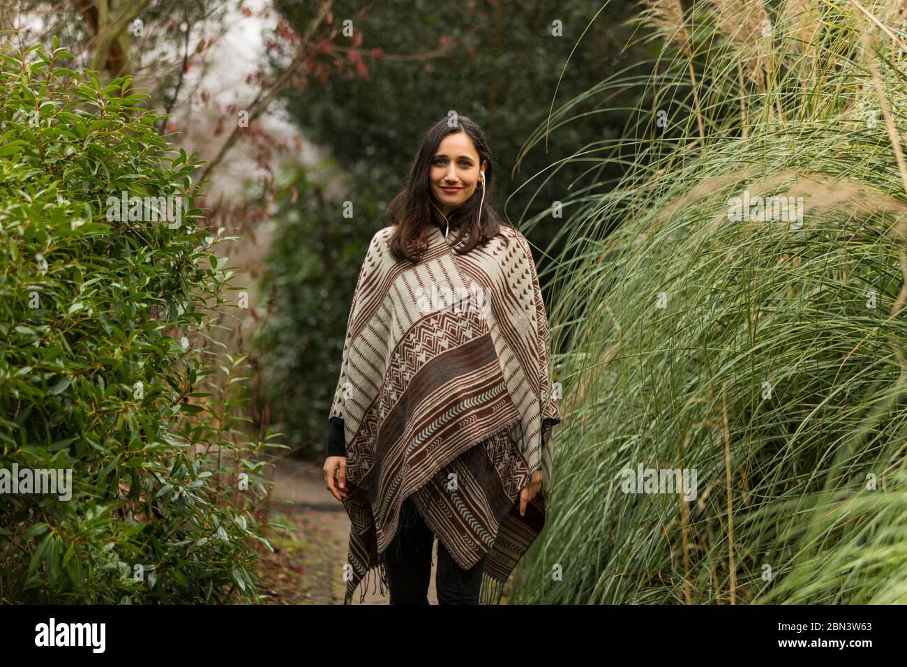 Giovane donna che indossa poncho in piedi tra erba alta in autunno Foto  stock - Alamy