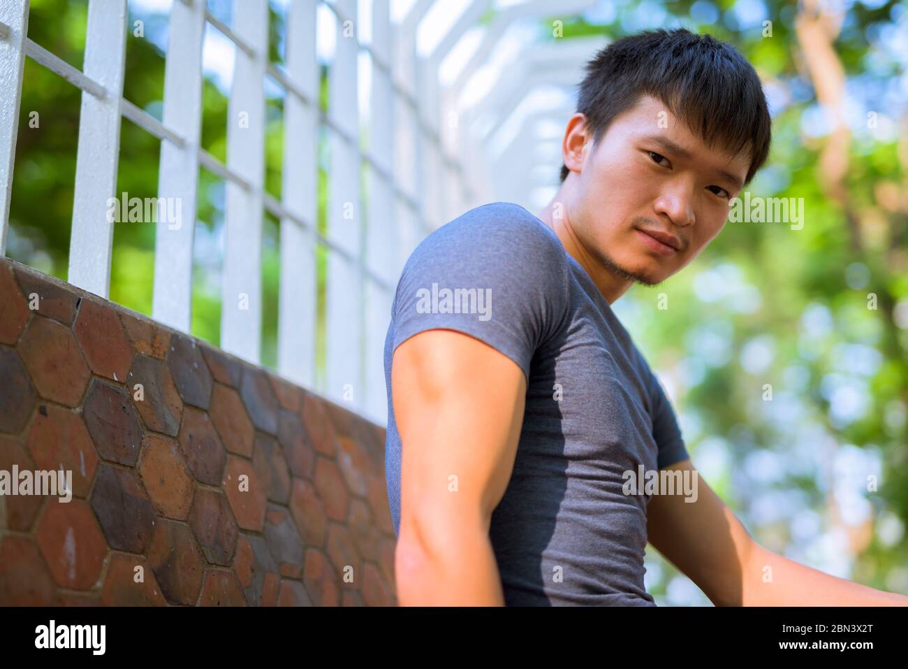 Ritratto di giovane asiatico seduto al parco all'aperto Foto Stock
