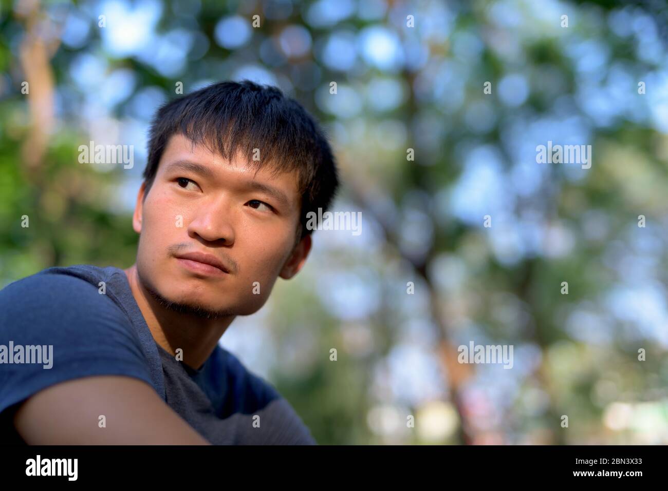 Ritratto di giovane asiatico che pensa al parco all'aperto Foto Stock
