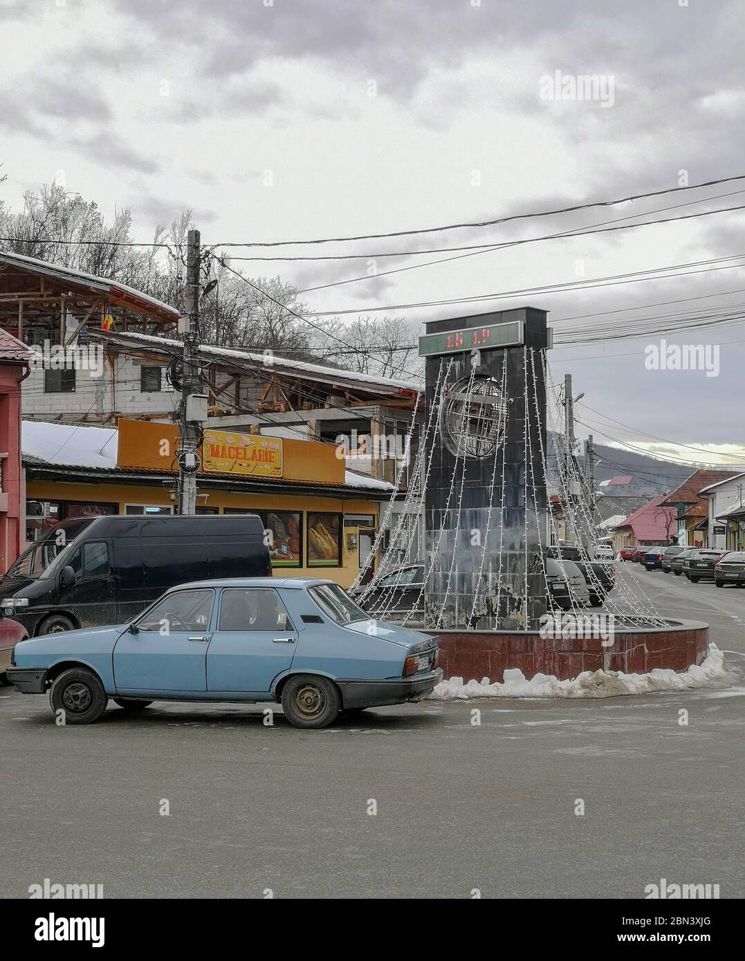 Una rotonda che segnala la presenza di una longitudine parallela di 45 gradi attraverso un piccolo villaggio in Romania chiamato Baia de Arama, con un vecchio dac blu Foto Stock