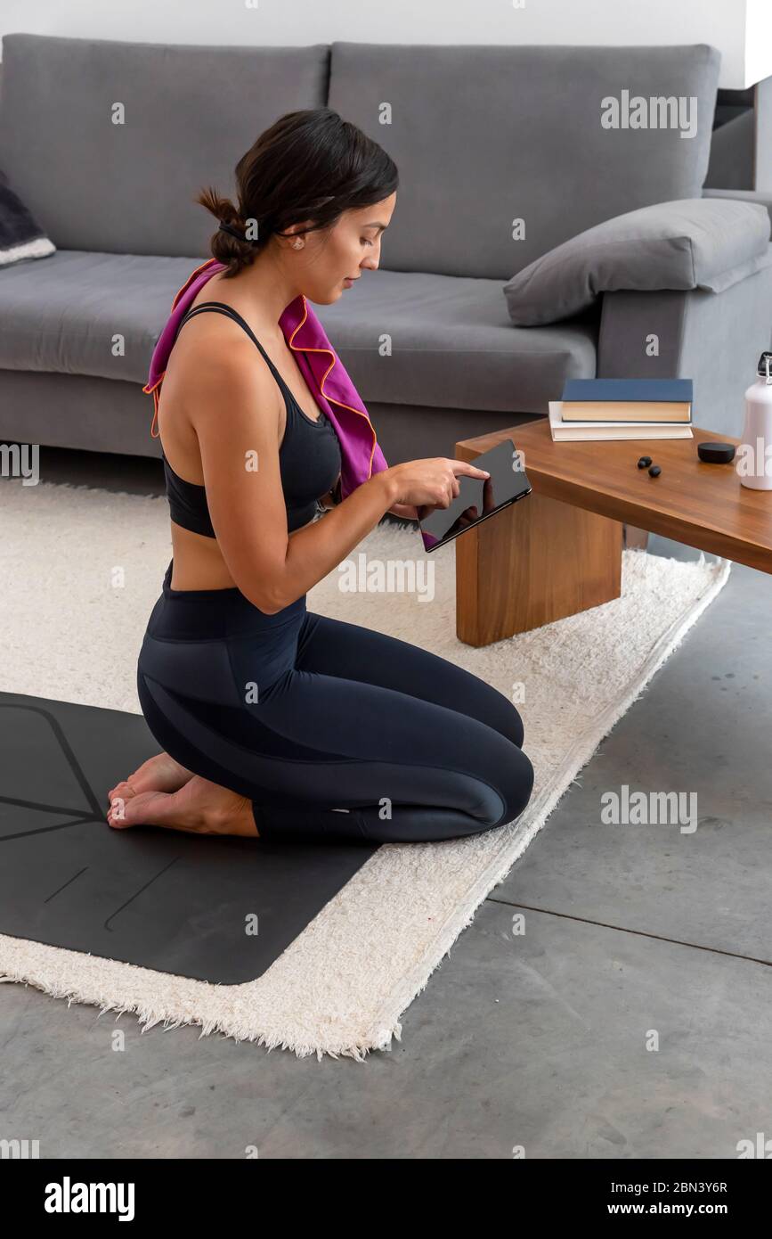 Donna riposata dopo aver praticato una sessione di yoga online a casa Foto Stock